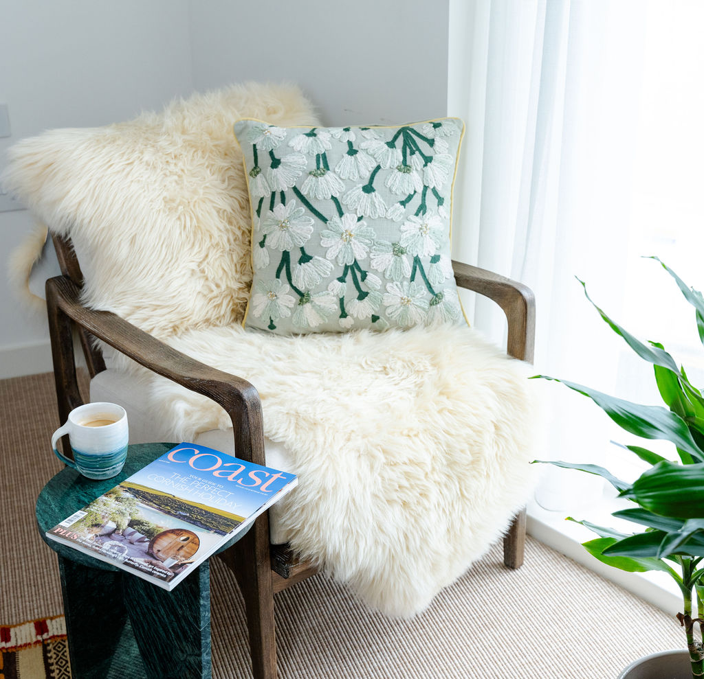 Sheepskin-draped reading chair beside a sunlit window